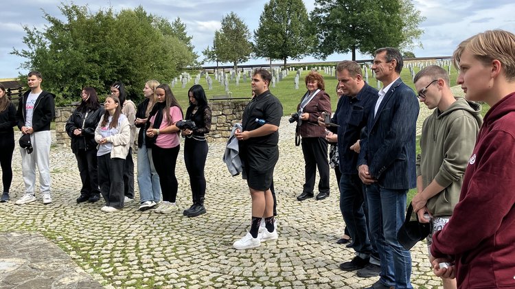 Eine Gruppe steht in einem Halbkreis versammelt für ein gemeinsames Gedenken. 