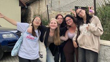 Eine Gruppe von fünf Teilnehmerinnen des Workcamps in der Nahaufnahme auf einem Parkplatz vor einer Mauer. Alle schauen fröhlich in die Kamera.